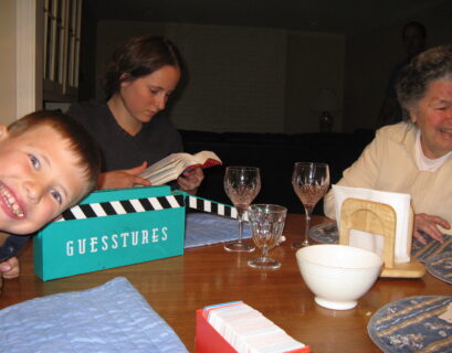 Family playing board game at dinner table.