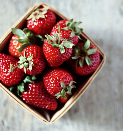 Basket of fresh red strawberries on table.