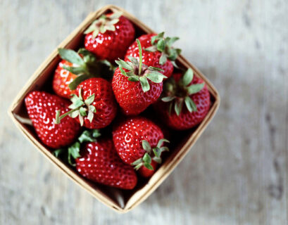 Basket of fresh red strawberries on table.
