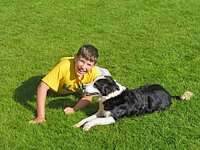 Boy playing with dog on grass lawn.