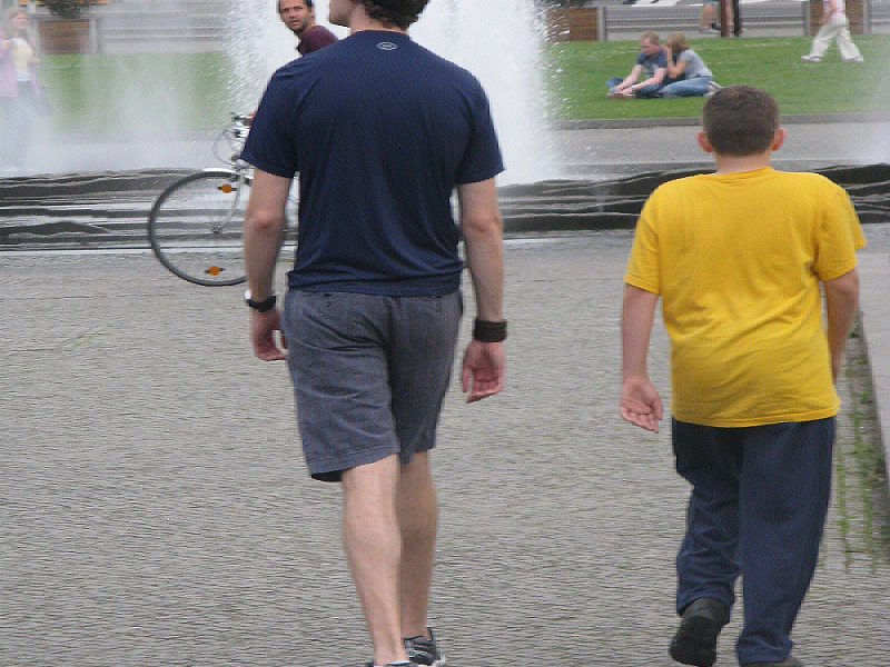 Two people walking near a fountain.
