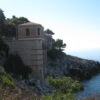 Coastal villa on rocky cliffside by sea.