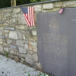 Memorial plaque with American flags on wall.