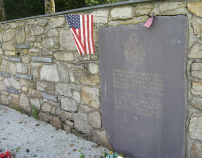 Memorial plaque with American flags on wall.