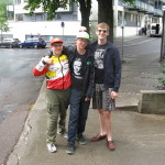 Three people standing on a city sidewalk.